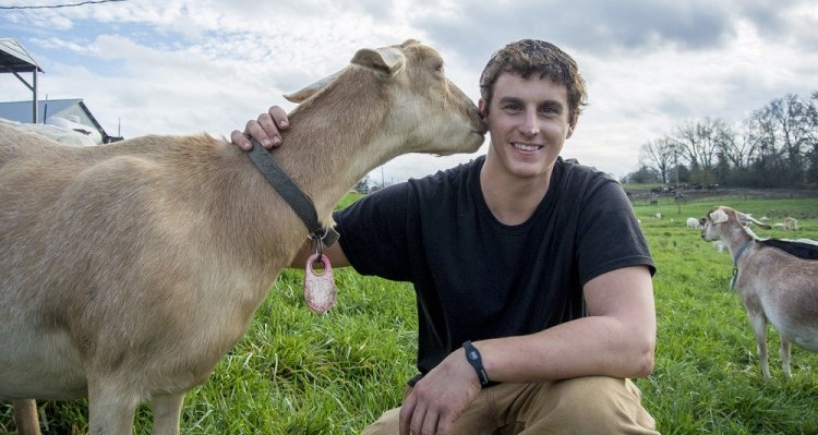Neill Lindley II poses with a goat that supplies milk for his family’s organic dairy farm. Credit: Triangle Land Conservancy
