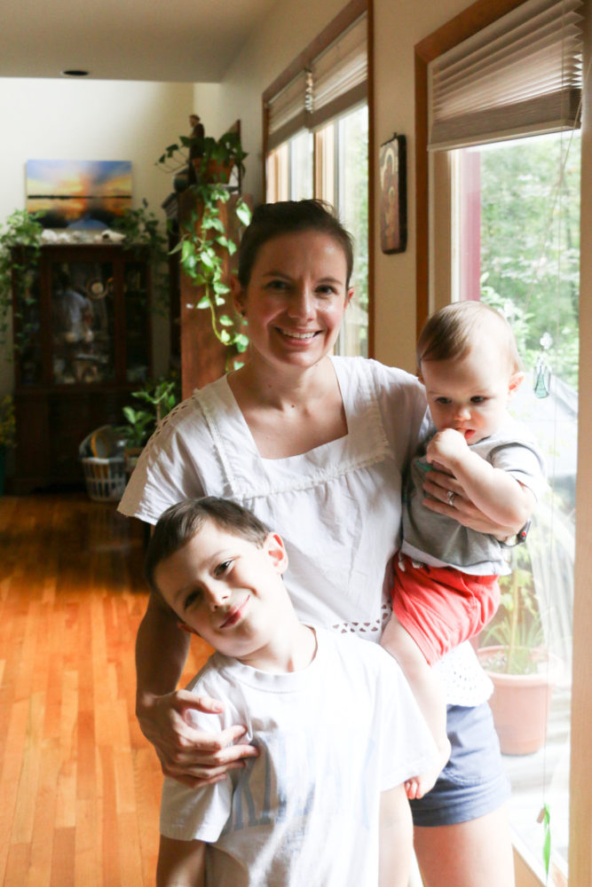 Marianna posing with her two sons in front of a window